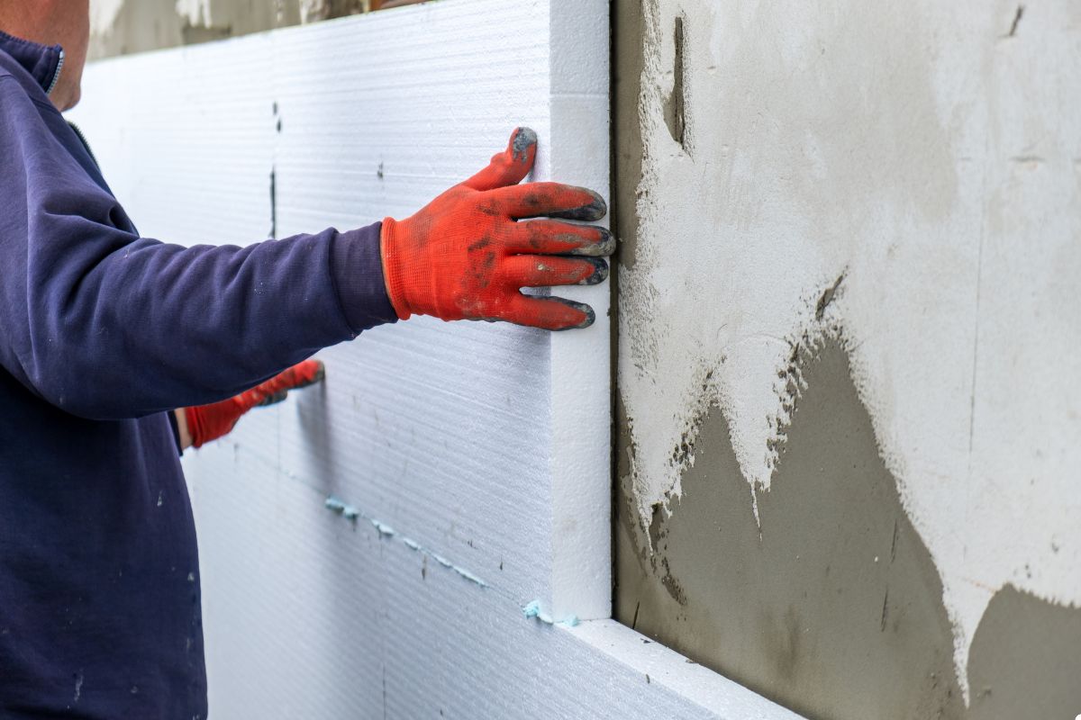  A man is seen covering a wall with cement, carefully working to ensure an even application.